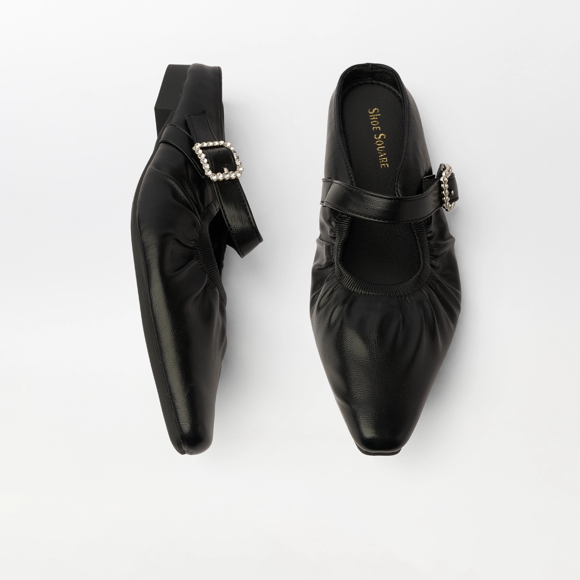 A pair of black Mary Jane flats by Saint Laurent, featuring a pointed toe, gathered elastic detail, and a silver-tone buckle embellished with small white crystals, shown on a clean white background.